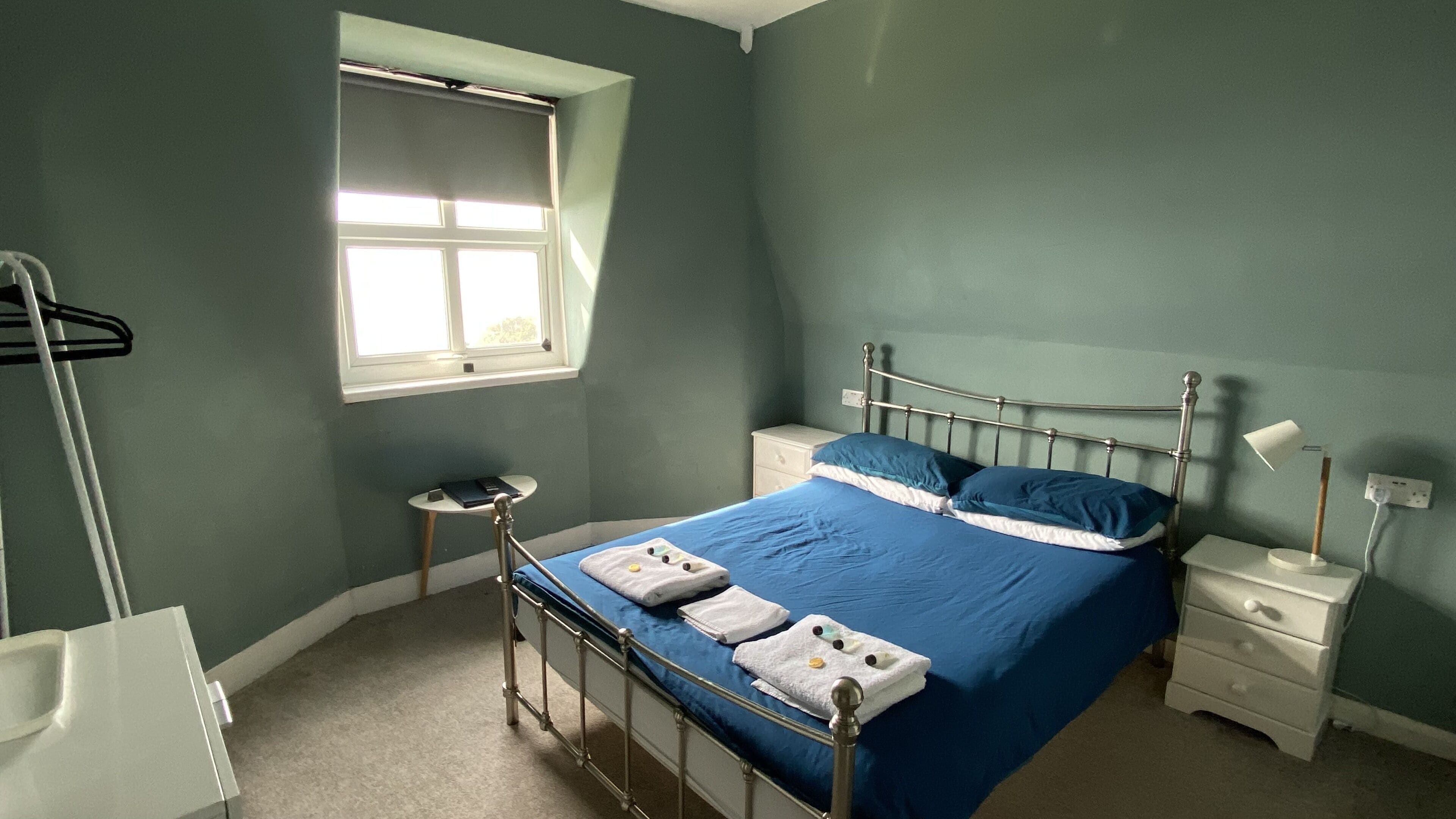 Een slaapkamer met een bed, twee nachtkastjes, een raam en een radiator.