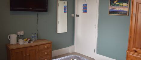 A bedroom with a bed, a dresser, a television, and a door with a poster.