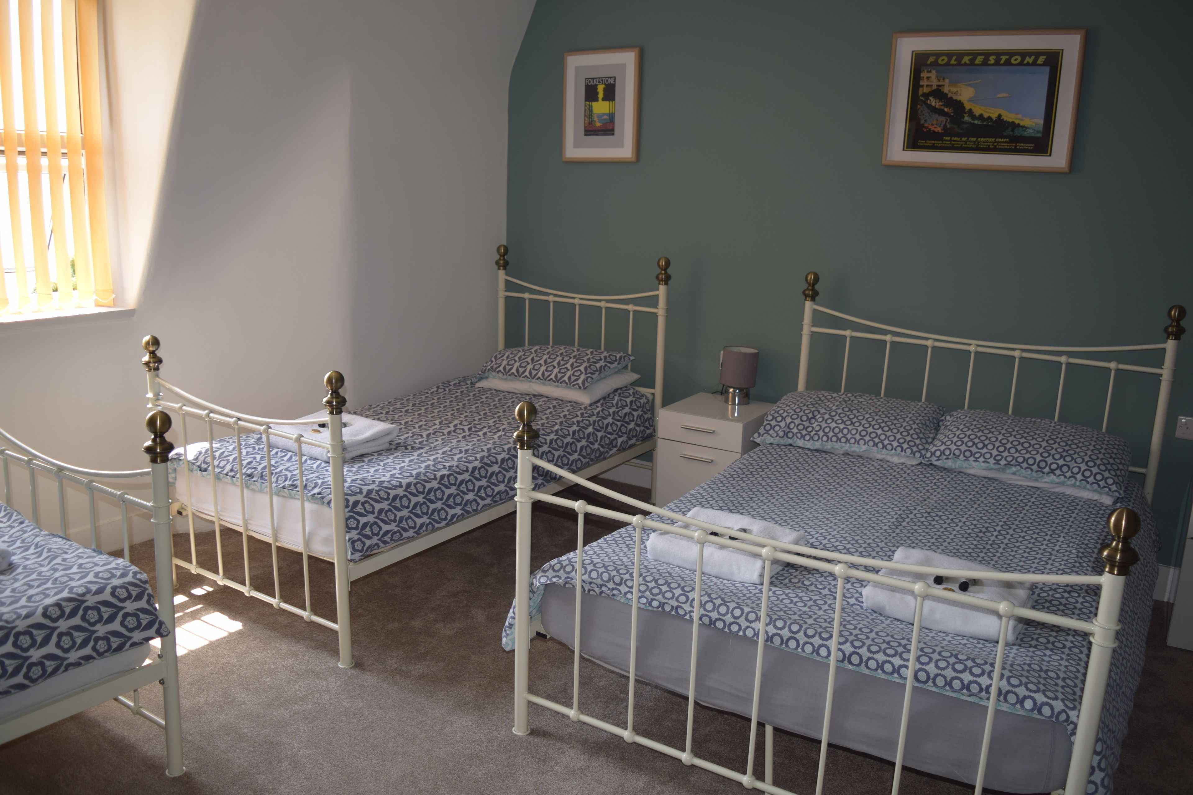 Un dormitorio con dos camas individuales y una cama doble más grande, todas con ropa de cama estampada.