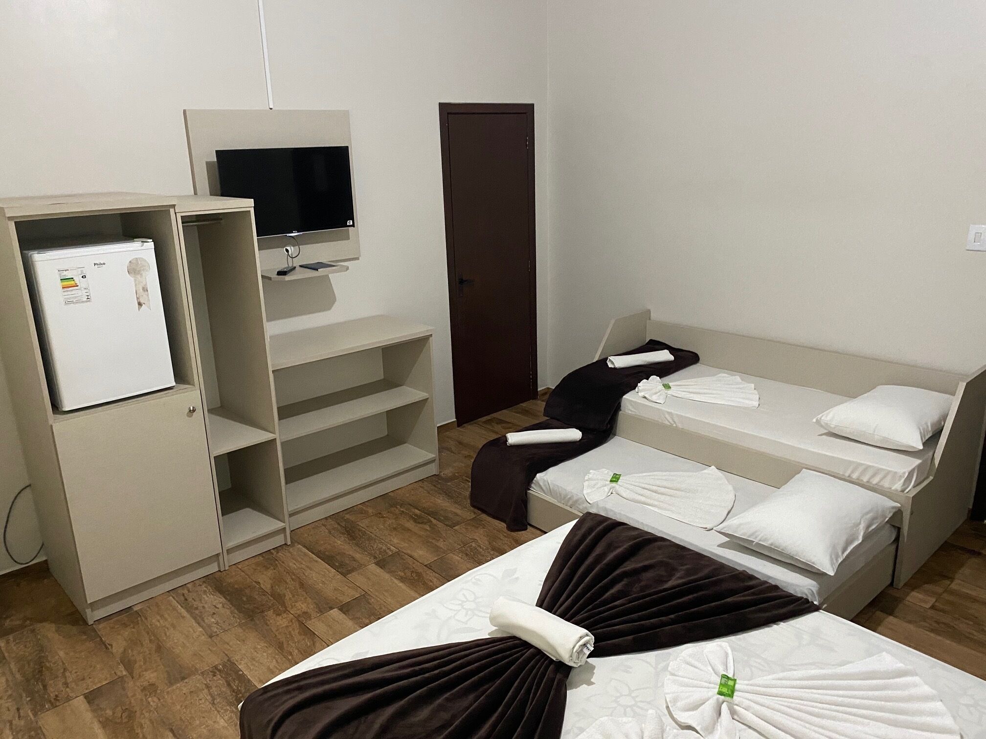 Habitación de hotel con cama, escritorio con computadora, televisor y armario.