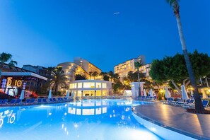 A swimming pool area with lounge chairs and a building with a curved facade. - Iz Flower Side Beach Hotel - All Inclusive (Manavgat)