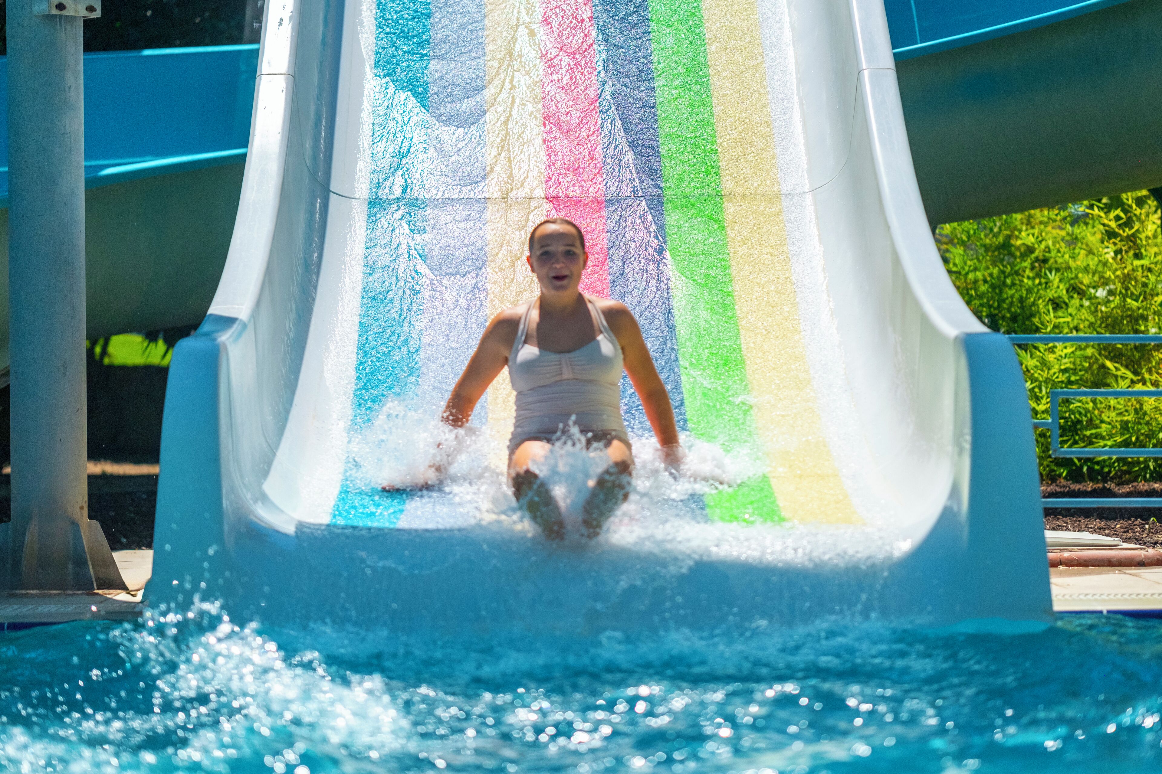 A person sliding down a water slide with a rainbow-colored interior.