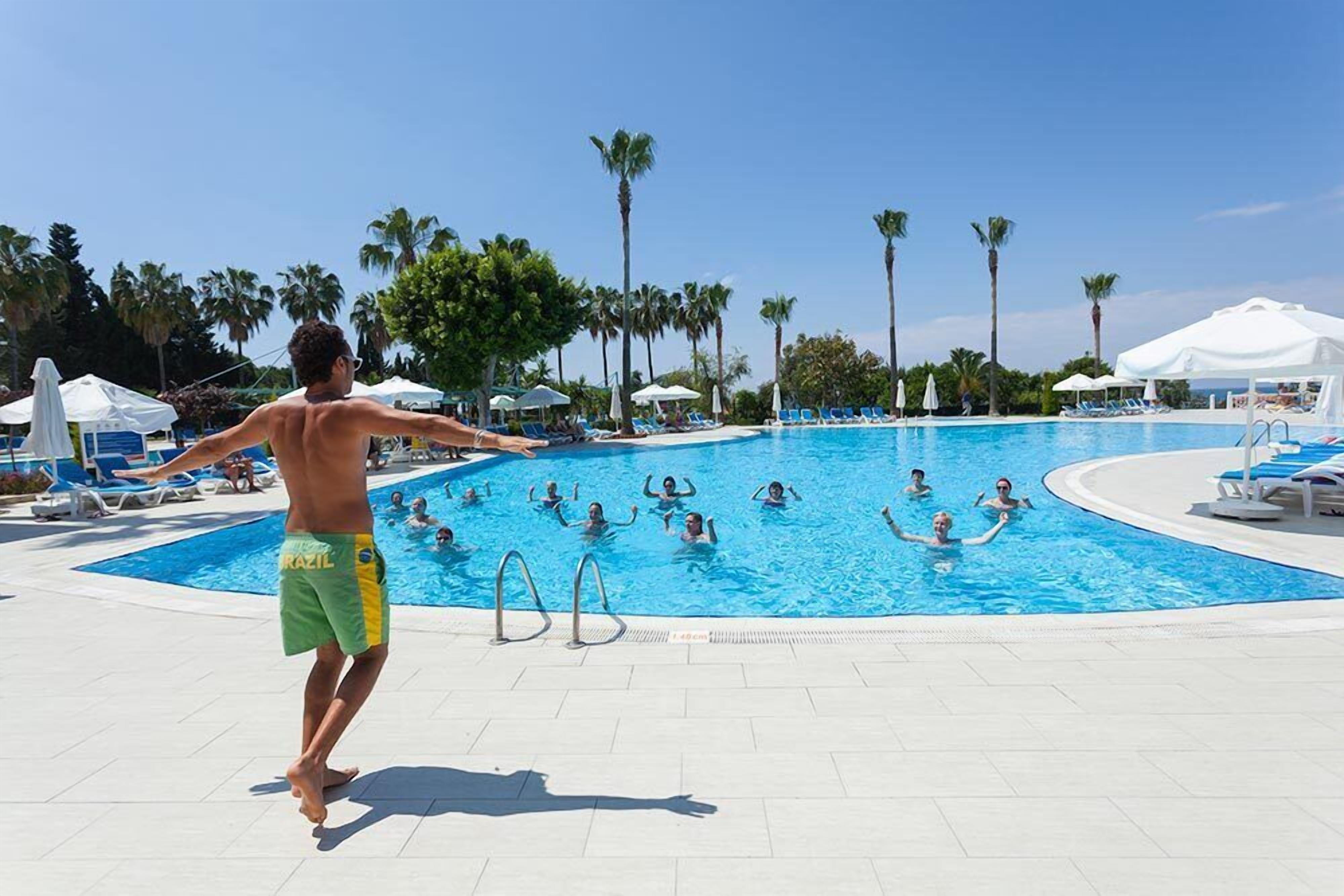 A swimming pool area with multiple pools, lounge chairs, and palm trees.