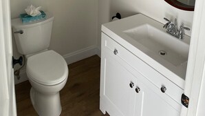 A bathroom with a toilet, a white sink, a mirror, and towel racks.