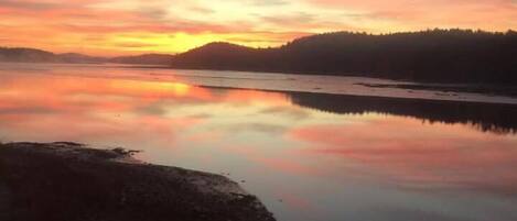 A calm lake at sunset with a wooden dock in the foreground.