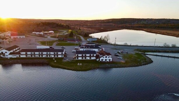 A lakeside hotel with a parking lot, a small dock, and a large body of water.