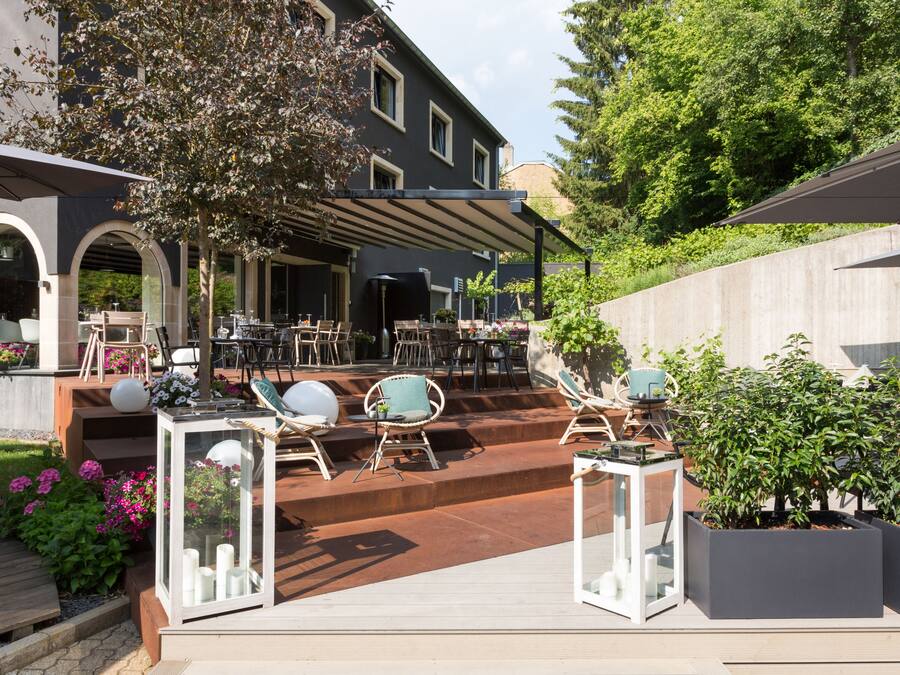 An outdoor patio area with multiple tables and chairs, a covered seating area, and potted plants.