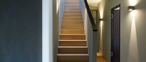 A modern staircase with wooden steps and a dark wall on one side.