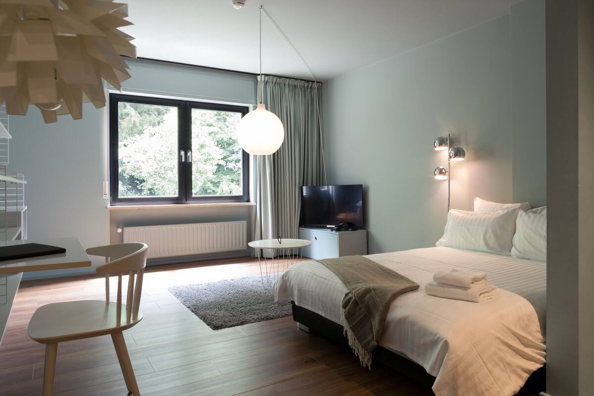 Een moderne slaapkamer met een bed, een televisie, een bureau en een stoel.