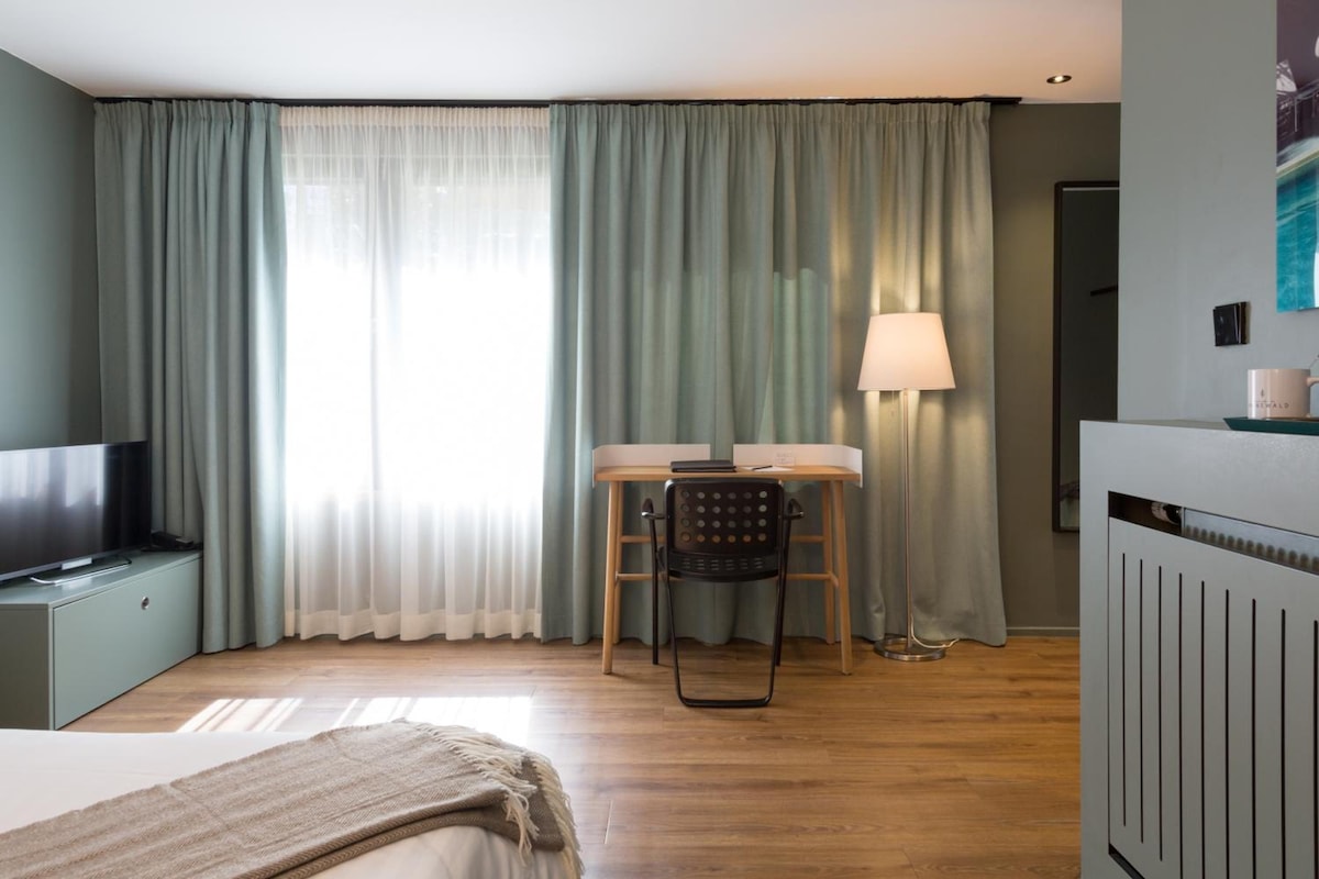 Una habitación de hotel con una cama, un escritorio con una silla, un televisor y una lámpara.