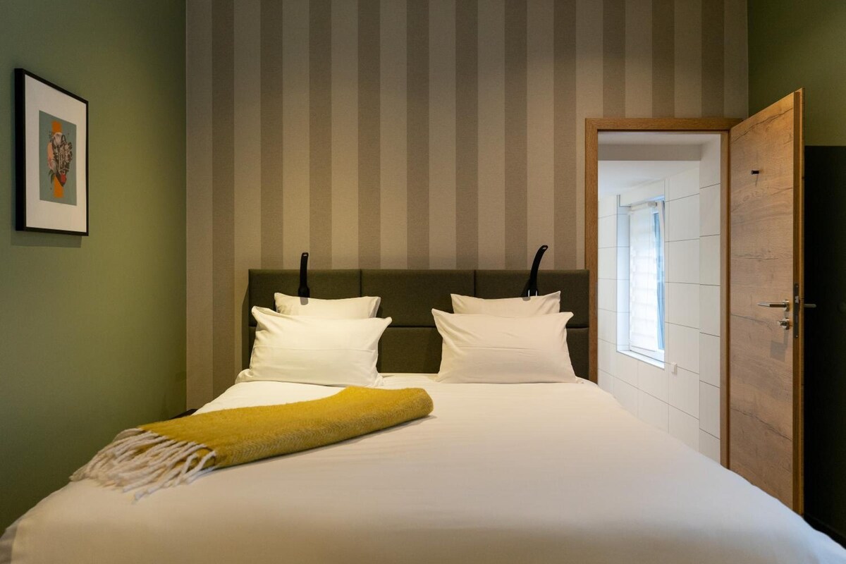 Una habitación de hotel con cama, puerta y ventana.