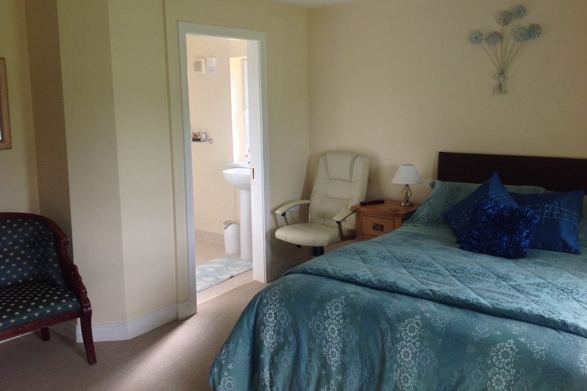 Une chambre à coucher comprenant un lit, une chaise, une table de chevet et un élément de décoration murale.