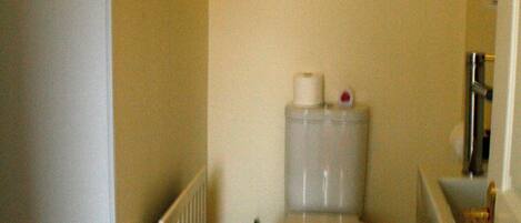 A small bathroom with a toilet, a radiator, and a painting on the wall.