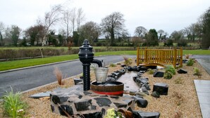 A garden with a stone fountain, a wooden bench, and a gravel path. - Ballyharvey House B&B (Antrim)