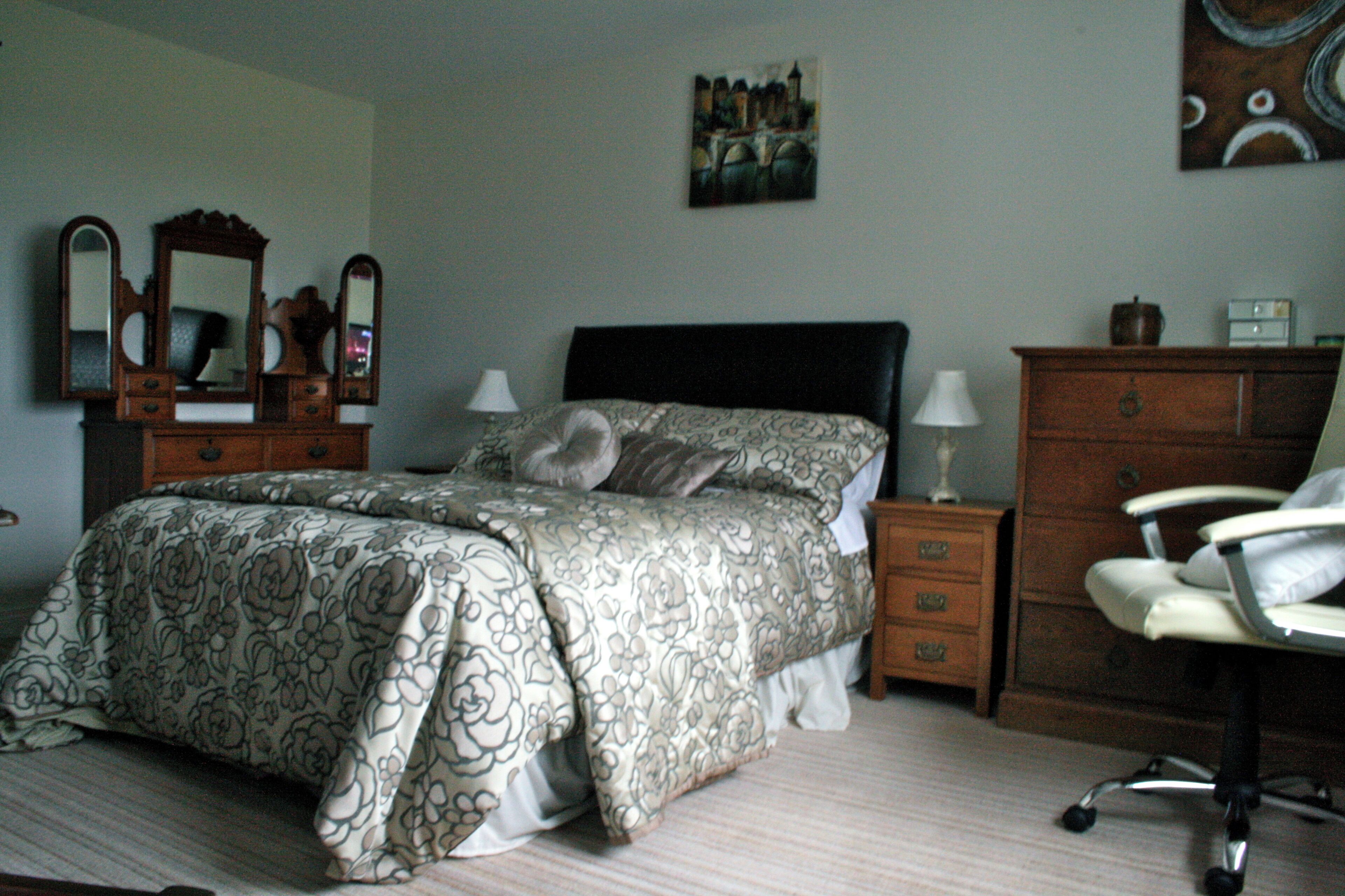 A bedroom with a bed, dresser, chair, and two bedside tables with lamps.