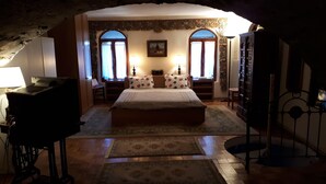 Una camera da letto con un letto grande, due comodini con lampade, una cassettiera e una televisione.