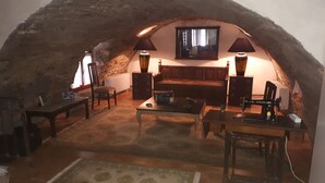 Una camera mansardata accogliente con un soffitto rustico in pietra, una panca di legno, un tavolo e due lampade.