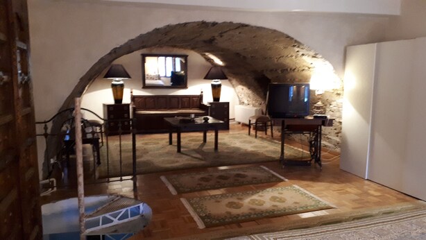 Una stanza soffitta accogliente con un arco in pietra, una televisione, un tavolo da pranzo e un divano.