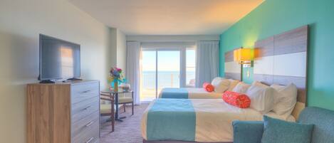 A hotel room with a bed, a TV, a desk, and a view of the outdoors.