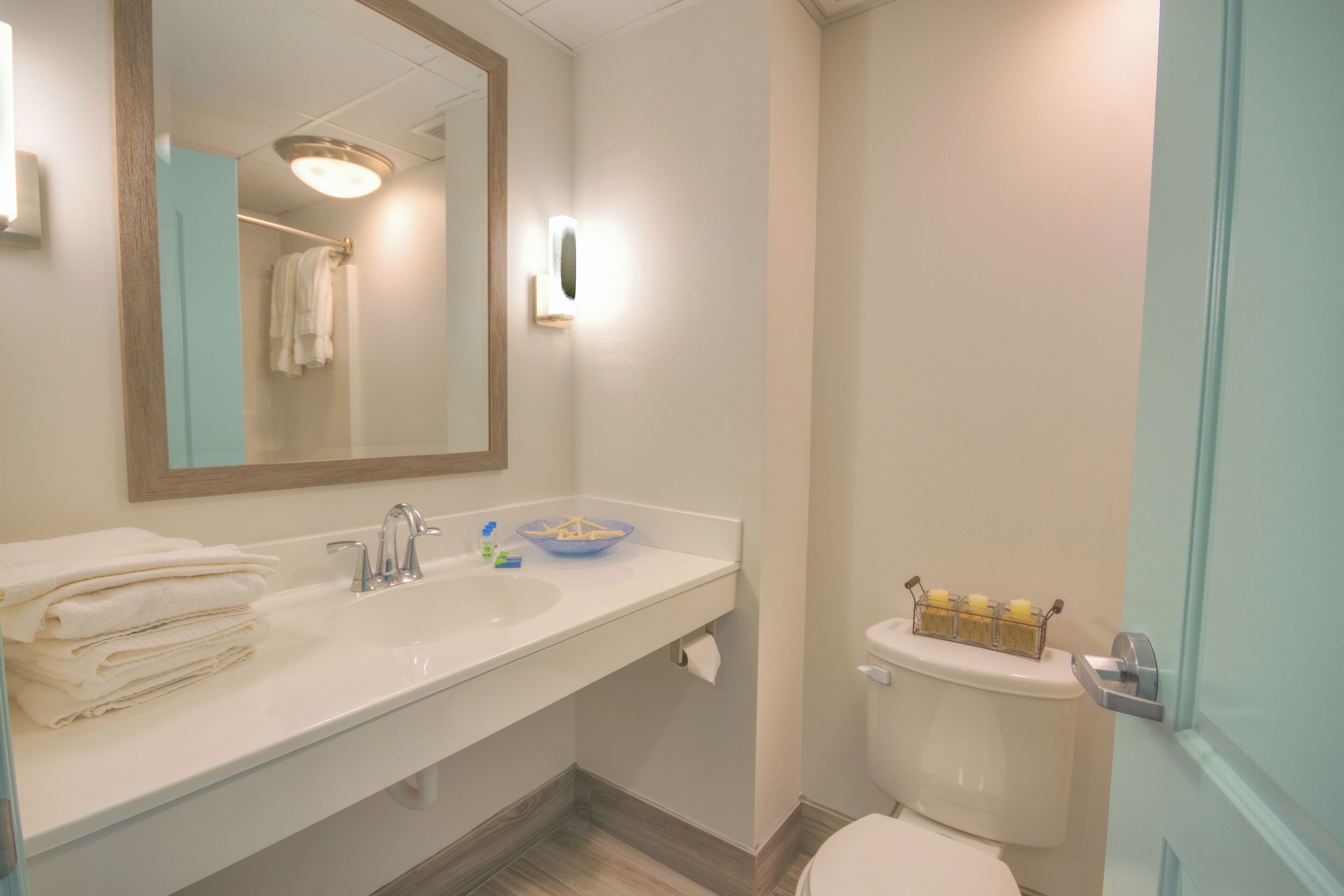 A bathroom with a white sink, a mirror, a toilet, and a towel rack.
