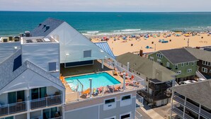 Un hôtel doté d’une piscine sur le toit, offrant une vue sur la plage, et dont l’architecture se caractérise par de nombreux étages.