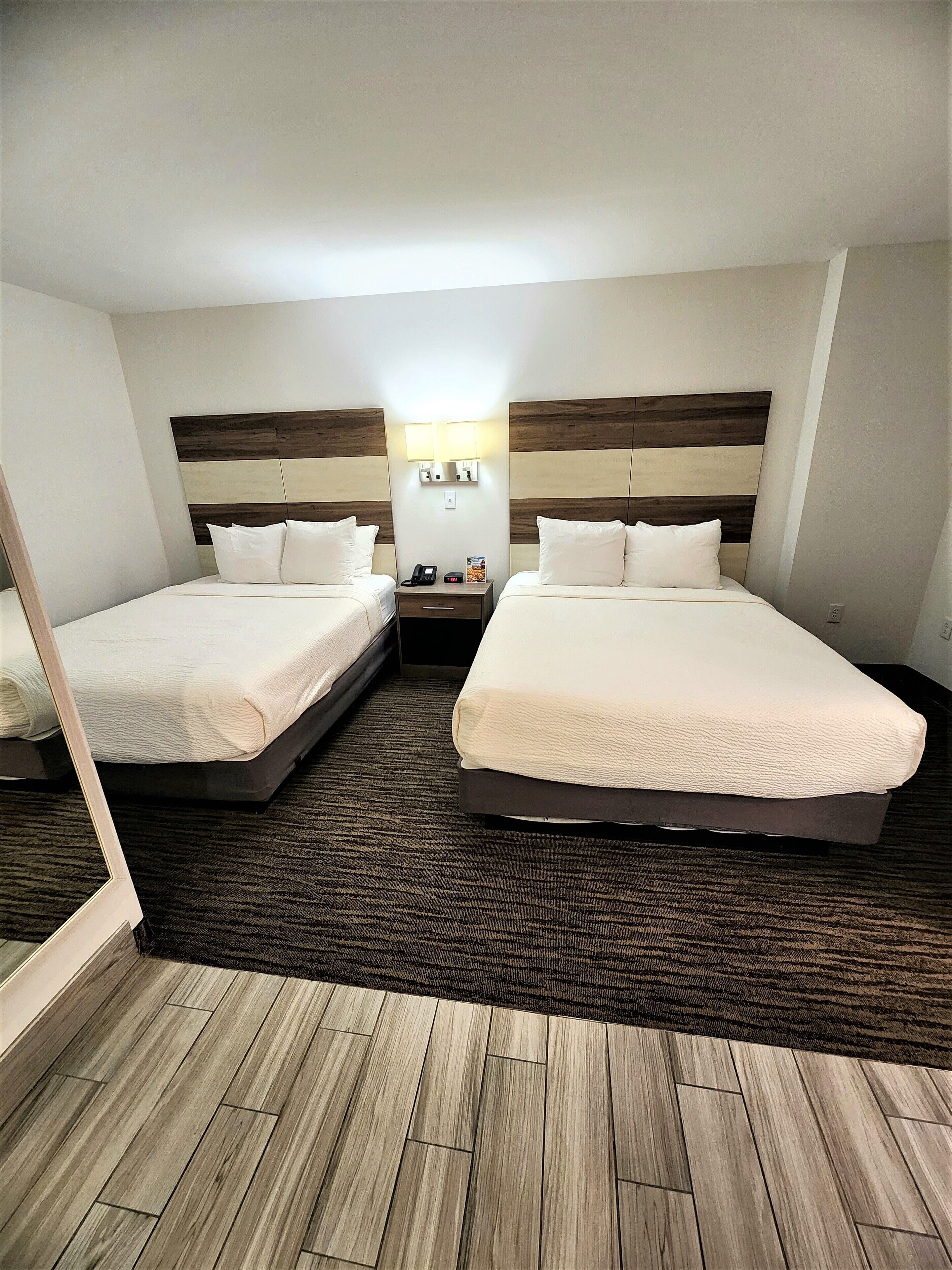 Een hotelkamer met twee bedden, een nachtkastje, een lamp en een vloerbedekking.