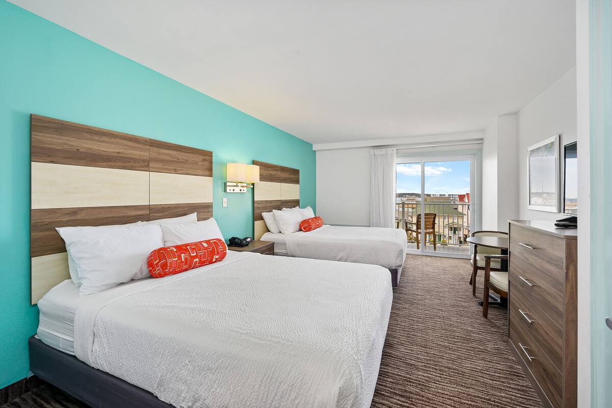 Une chambre d’hôtel avec deux lits, un bureau et une vue sur la ville.