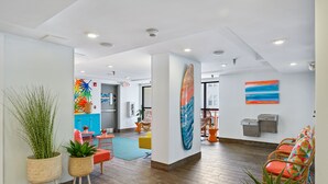 Un hall d’entrée moderne avec un revêtement de sol en bois, un comptoir d’accueil, des sièges aux couleurs vives et un grand tableau abstrait.
