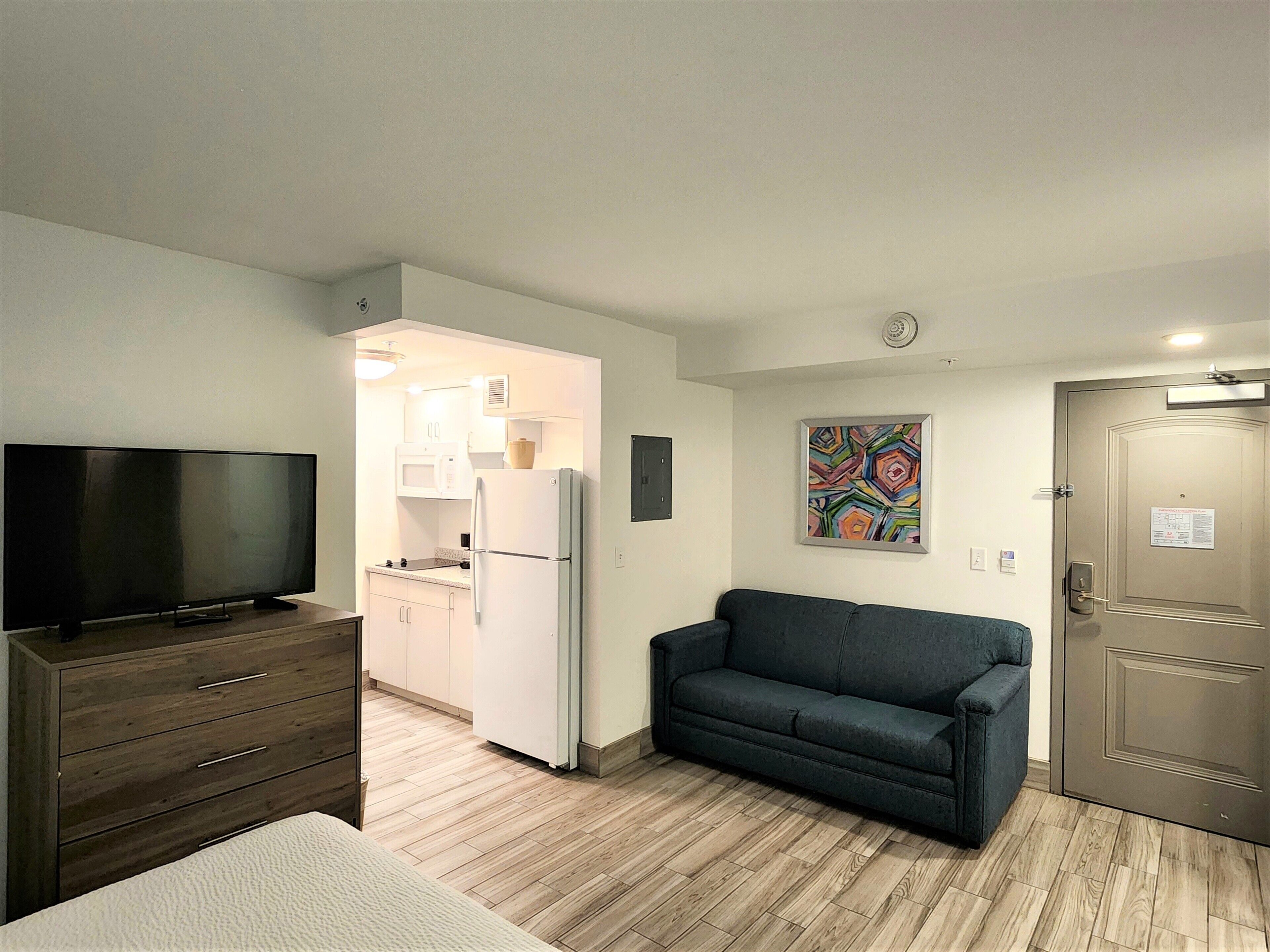 A compact living space with a TV, a sofa, a kitchenette, and a door.