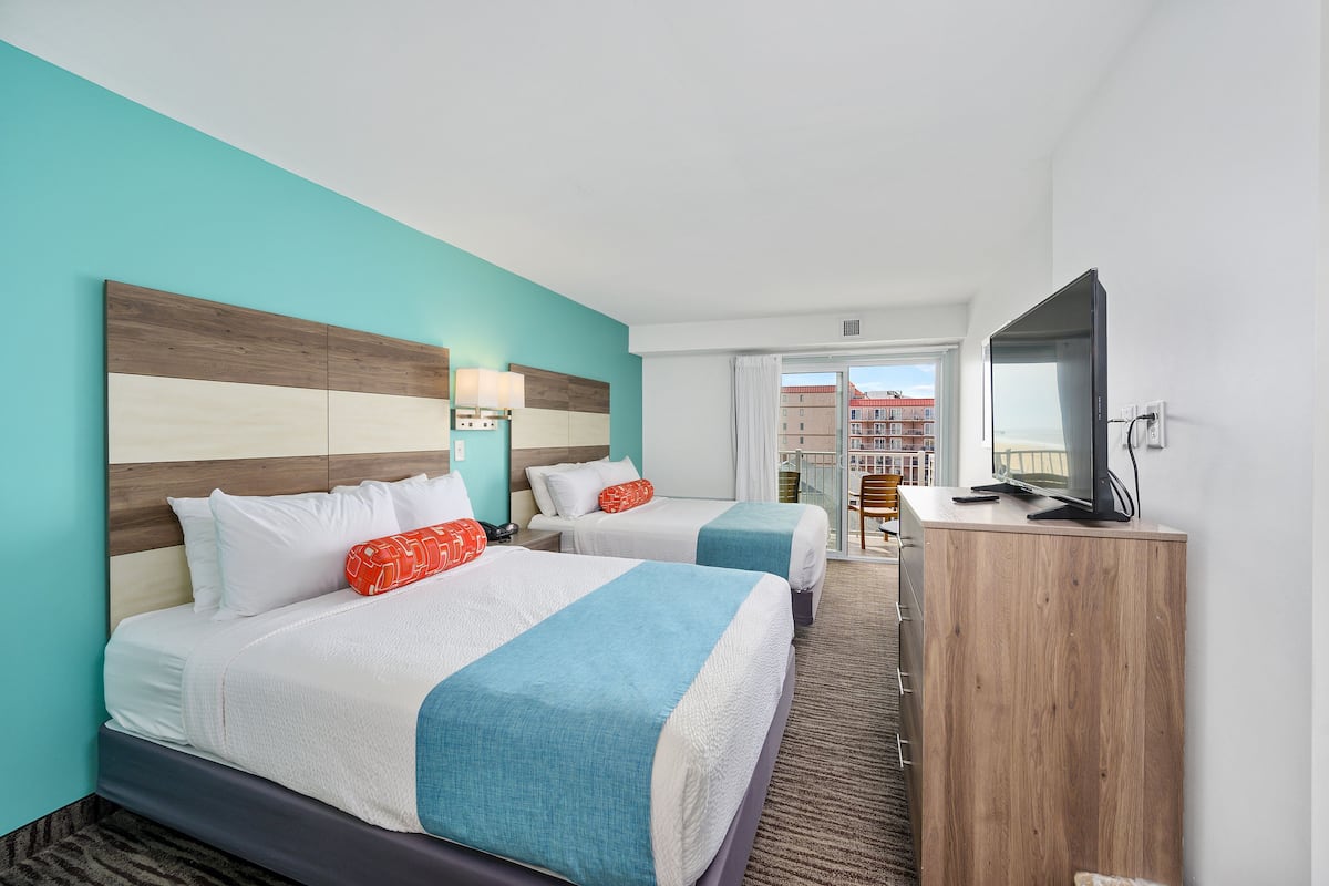 Une chambre d’hôtel avec deux lits, une télévision et une vue sur les bâtiments par la fenêtre.