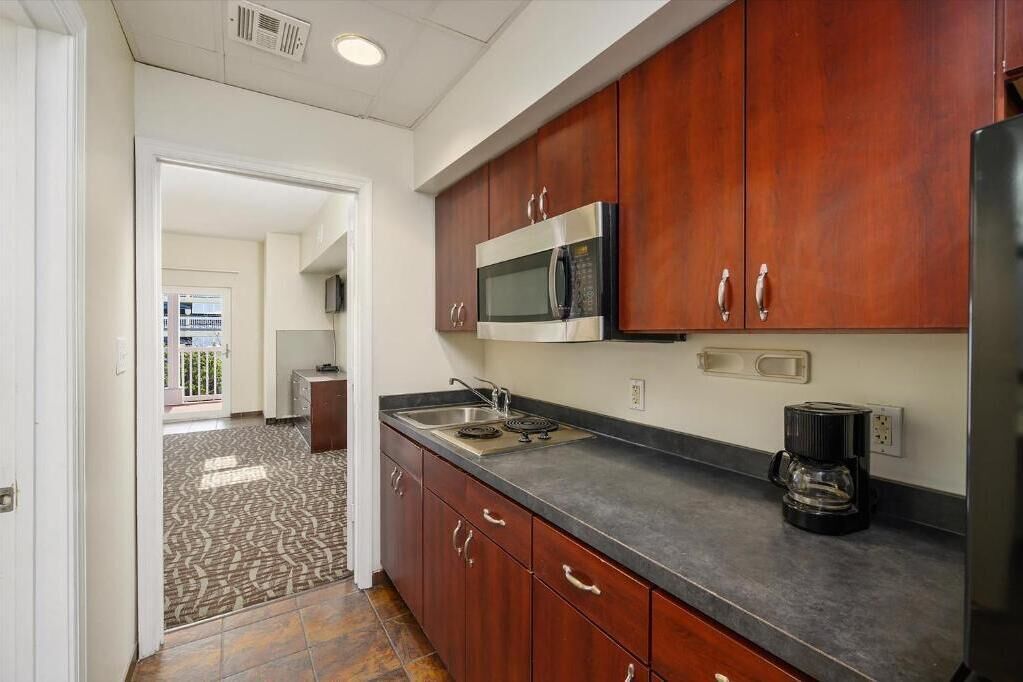 A kitchen with wooden cabinets, a stainless steel microwave, a coffee maker, and a sink.