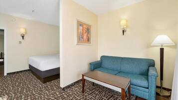 A hotel room with a bed, a blue sofa, a small table, and two wall-mounted lamps.