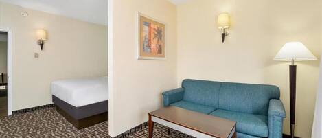 Een hotelkamer met een bed, een blauwe bank, een klein tafeltje en twee wandlampen.