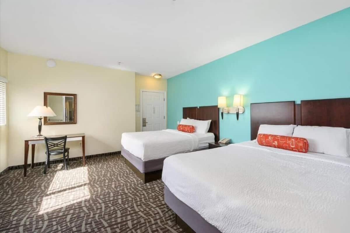 Une chambre d’hôtel avec deux lits, un bureau et une chaise.