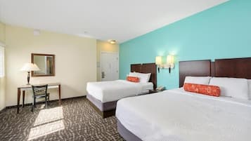 A hotel room with two beds, a desk, and a chair.