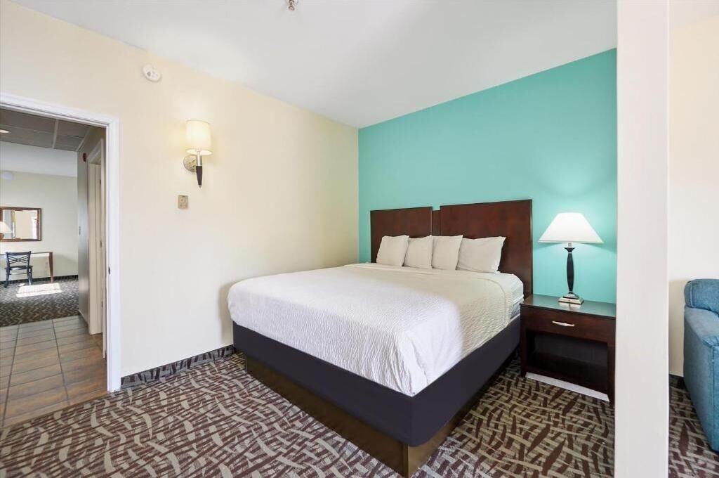 Une chambre d’hôtel avec un lit, une table de chevet, une lampe et un sol à motifs.