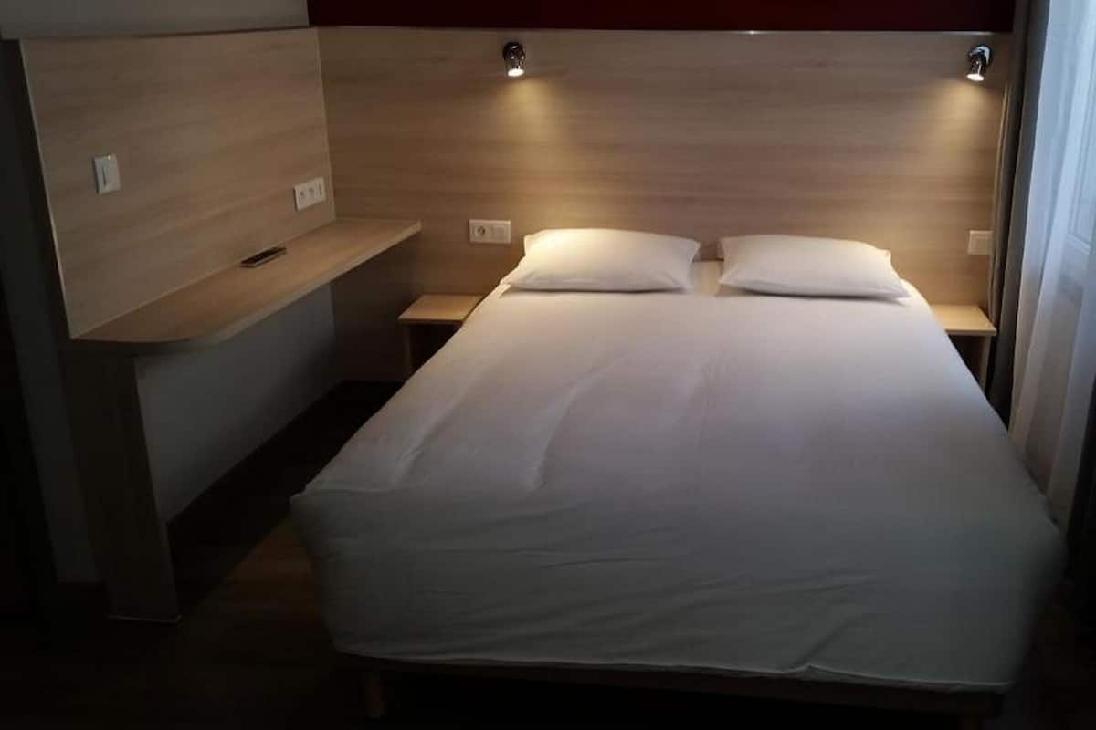 A single bed with a wooden headboard, bedside tables, and a small shelf.