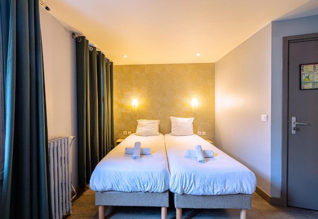 A hotel room with two beds, a radiator, curtains, and a door.