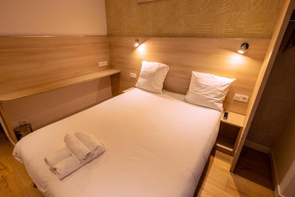 A hotel room with a bed, two bedside tables, and a headboard with built-in lighting.
