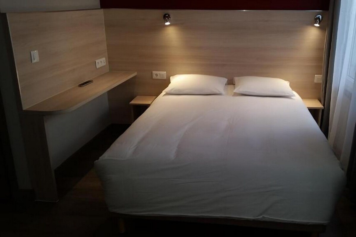 A single bed with a wooden headboard, bedside tables, and a small shelf.