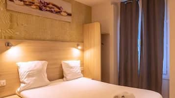 Ein Hotelzimmer mit Bett, Nachttischen, Kopfteil und einem an der Wand hängenden Kunstwerk.