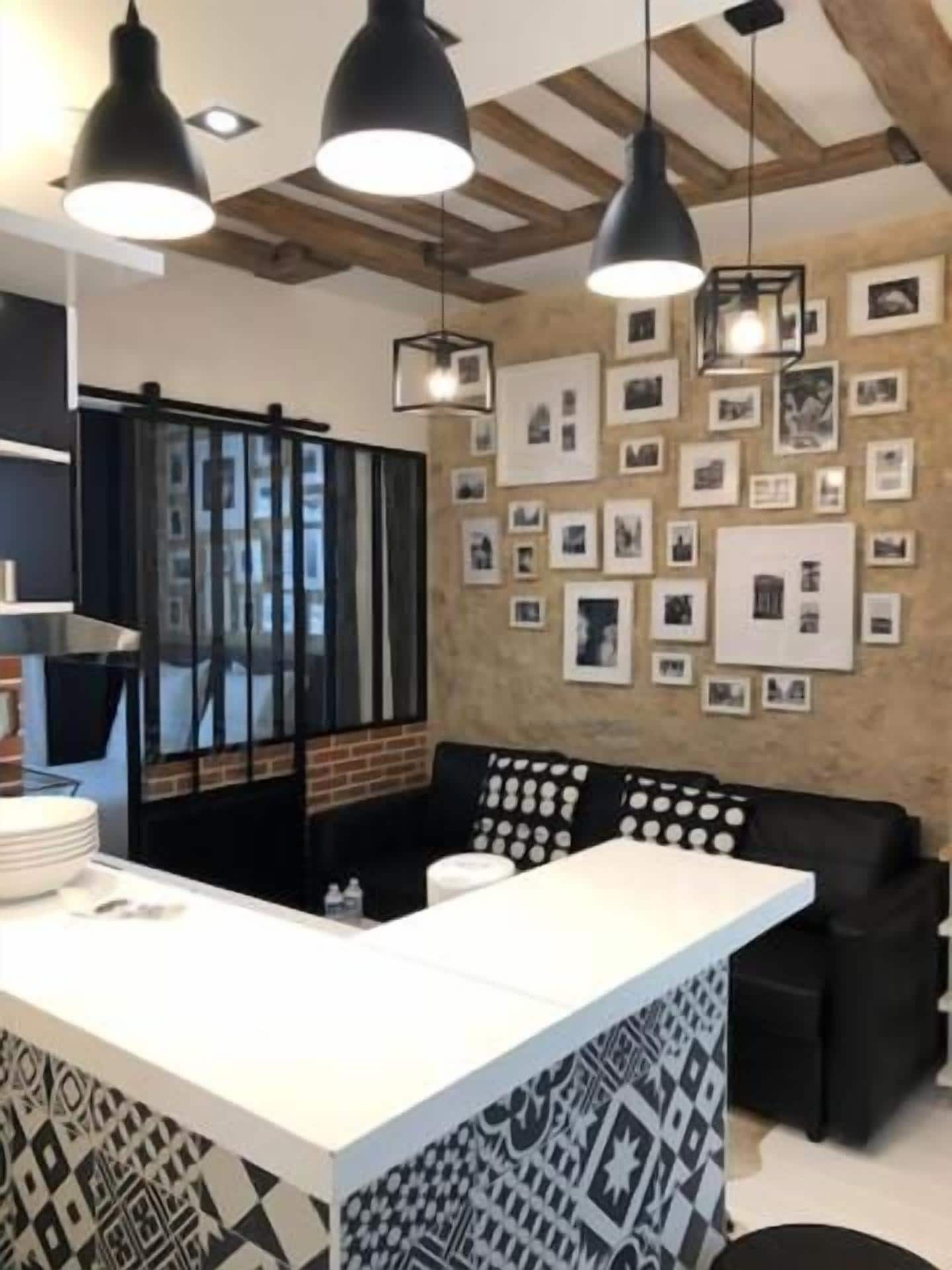 A modern kitchen with a central island, pendant lighting, and a wall adorned with framed photos.