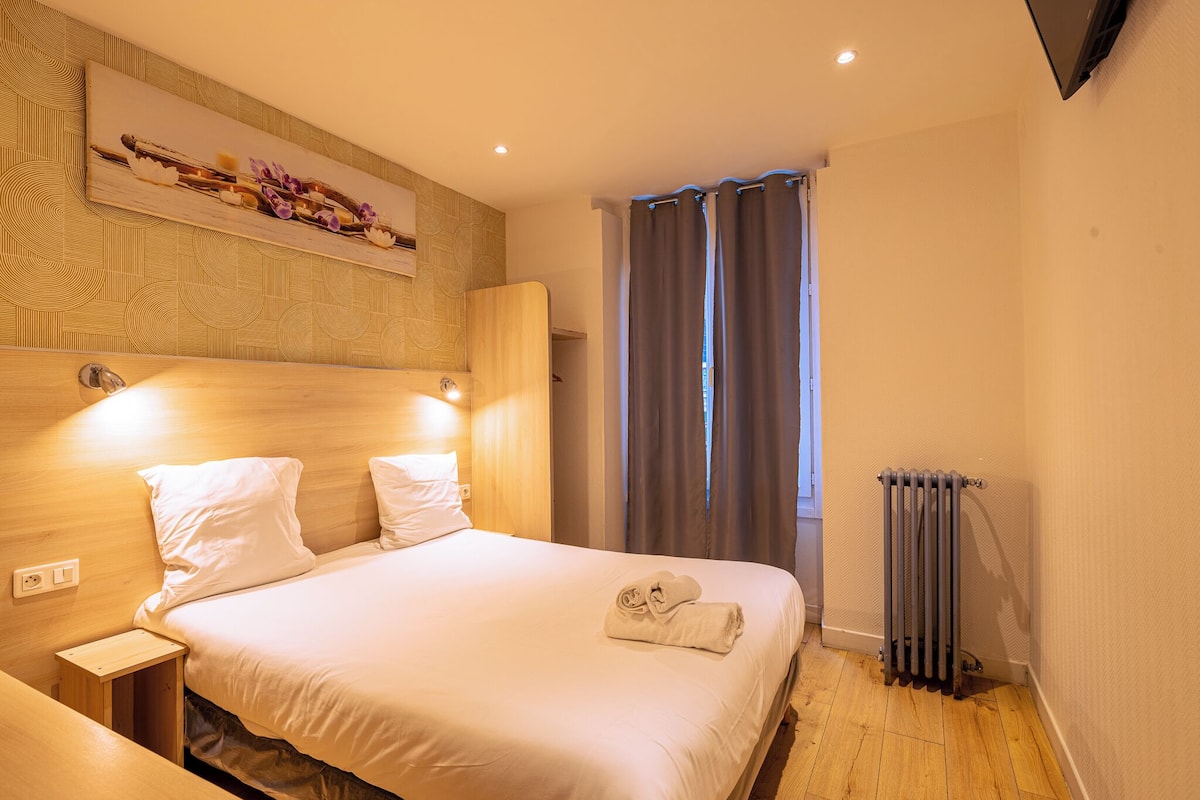 A neatly made bed with white linens, a wooden headboard, and a small bedside table with a lamp.