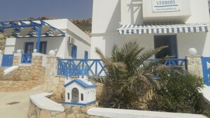 A building with a sign reading "Blue and White Studios" and a small model house in front. - Blue and White Studios & Apartments (Karpathos)