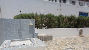 A stone-tiled outdoor area with a mosaic wall and a stone bench. - Blue and White Studios & Apartments (Karpathos)