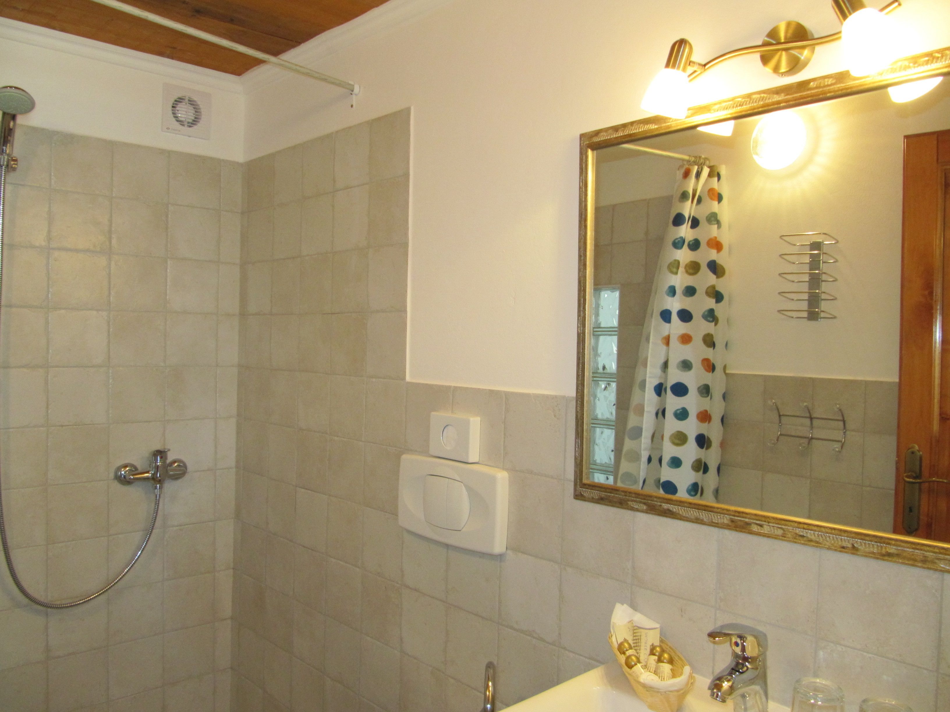 A bathroom with a shower, a sink, a mirror, and a towel rack.