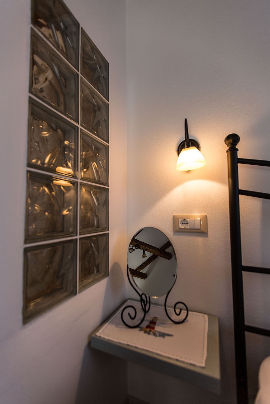 A bathroom with a mirror, a light fixture, and a wall-mounted outlet.