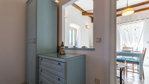 A room with a light blue cabinet, a mirror, a dining table with chairs, and a window with curtains. - Apartments Casa Saina (Rovinj)