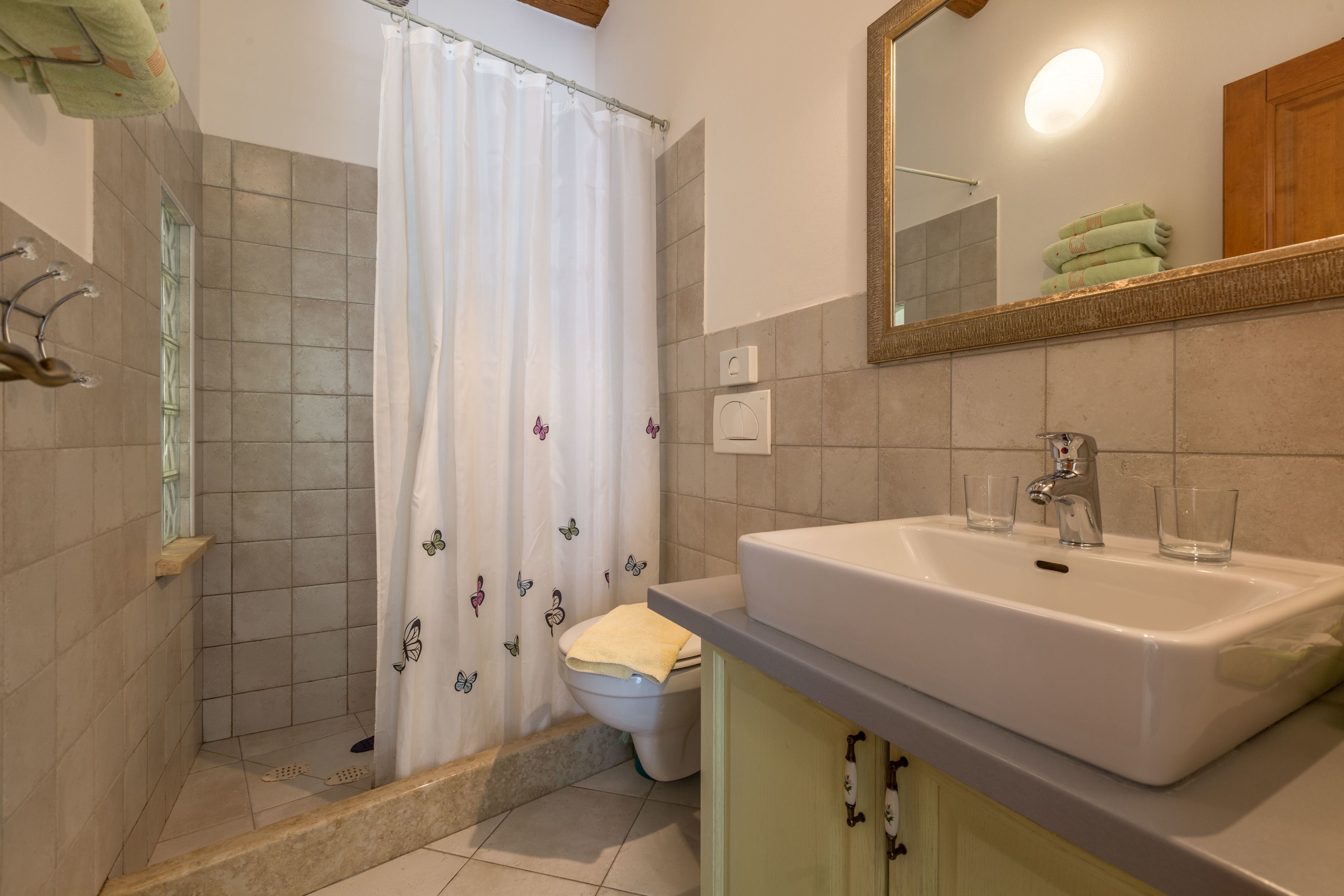 A bathroom with a shower, toilet, sink, and mirror.