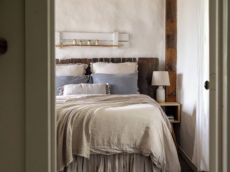 Une chambre à coucher avec une tête de lit en bois, une table de chevet avec une lampe et une fenêtre avec des rideaux.
